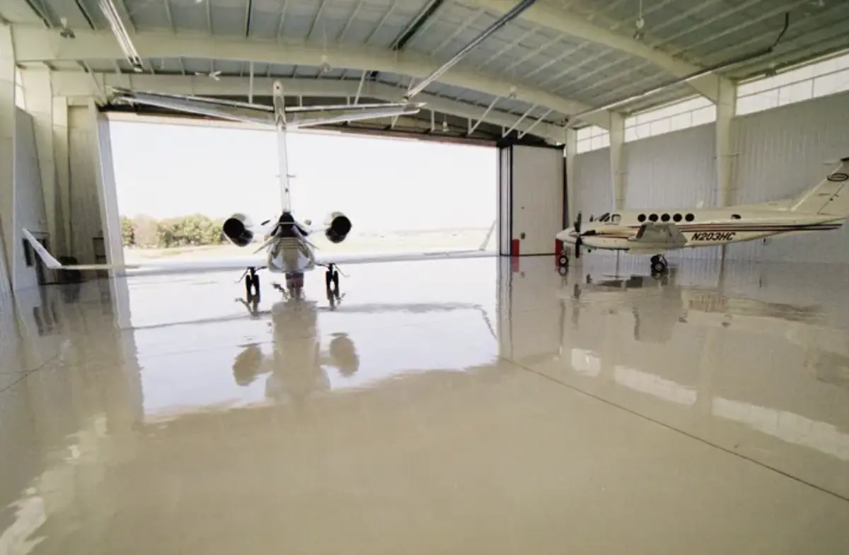 A plane is parked in a hangar with the door open.