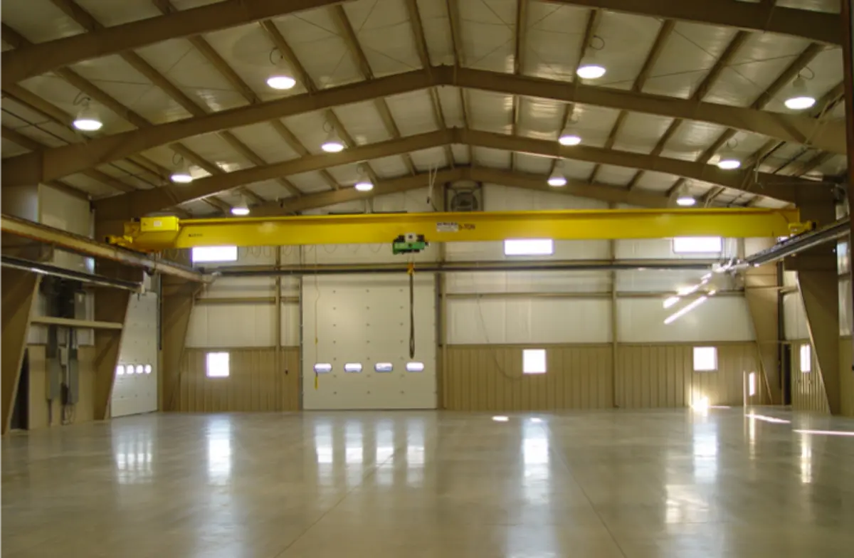 An empty warehouse with a yellow crane on top of it