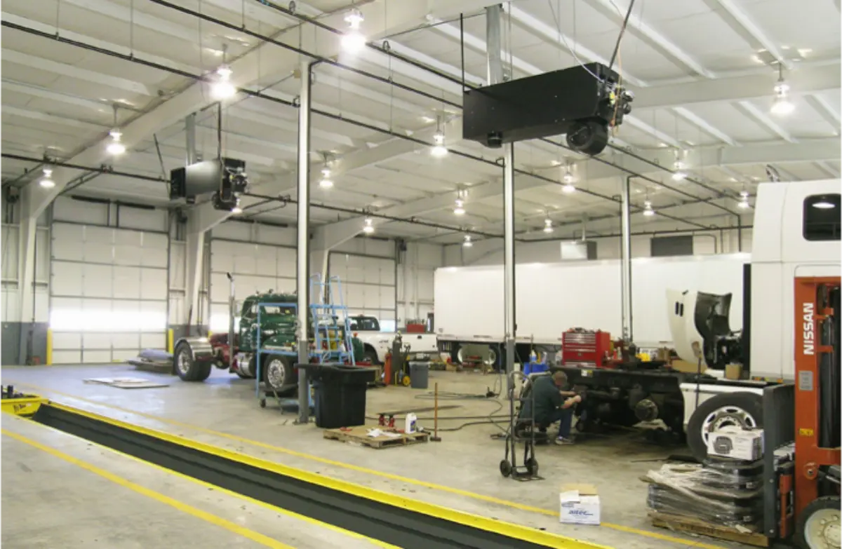 A man is working on a truck in a large garage