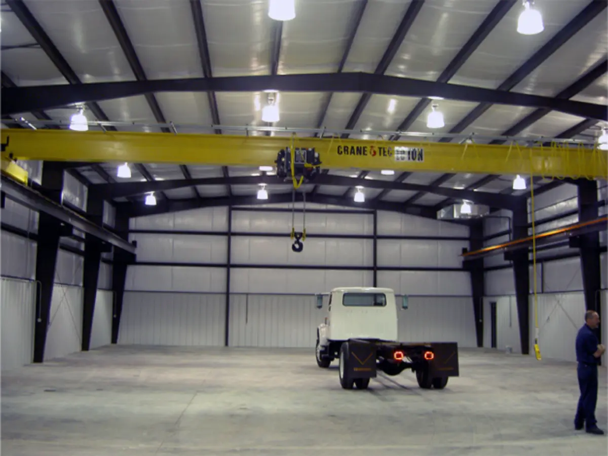 A truck is being lifted by a crane in a warehouse