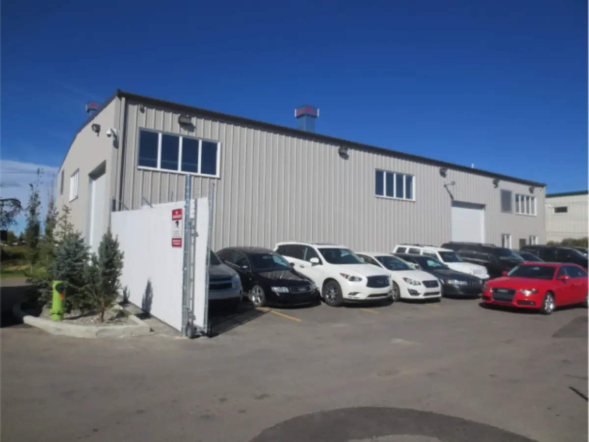 A row of cars are parked in front of a building