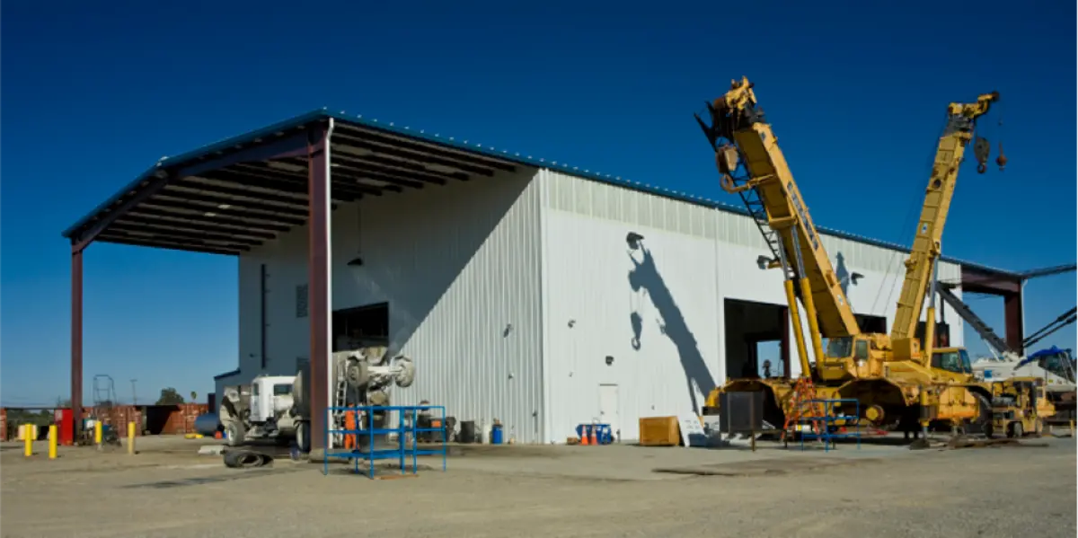 A large yellow crane is parked in front of a building.