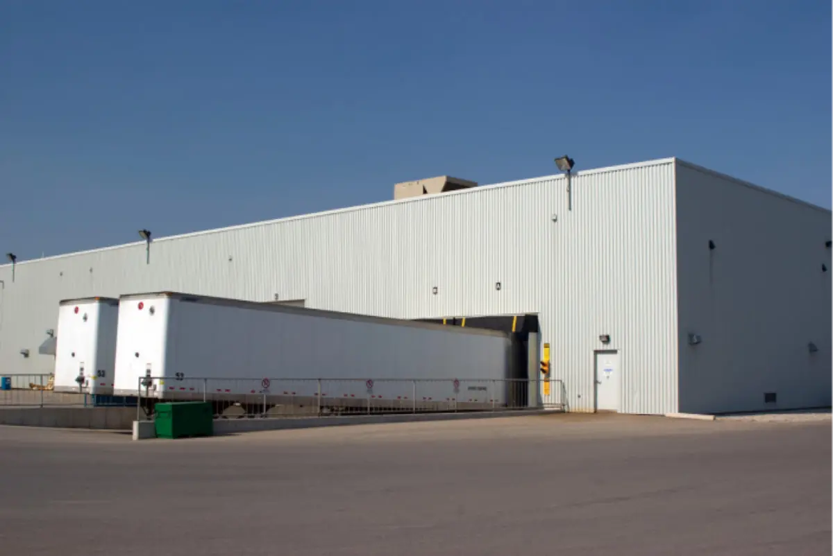 A large white building with two white trailers parked in front of it