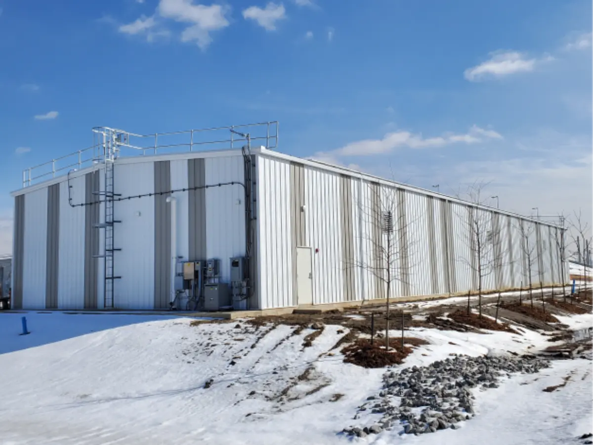 A large white building is sitting in the middle of a snowy field.