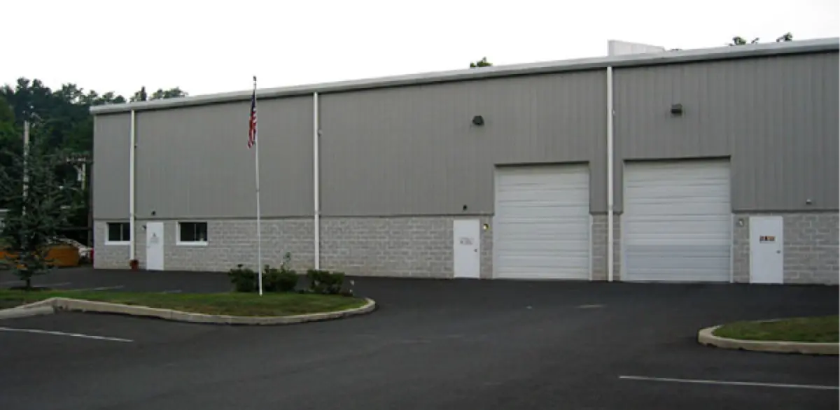 A large building with white garage doors and a flag in front of it