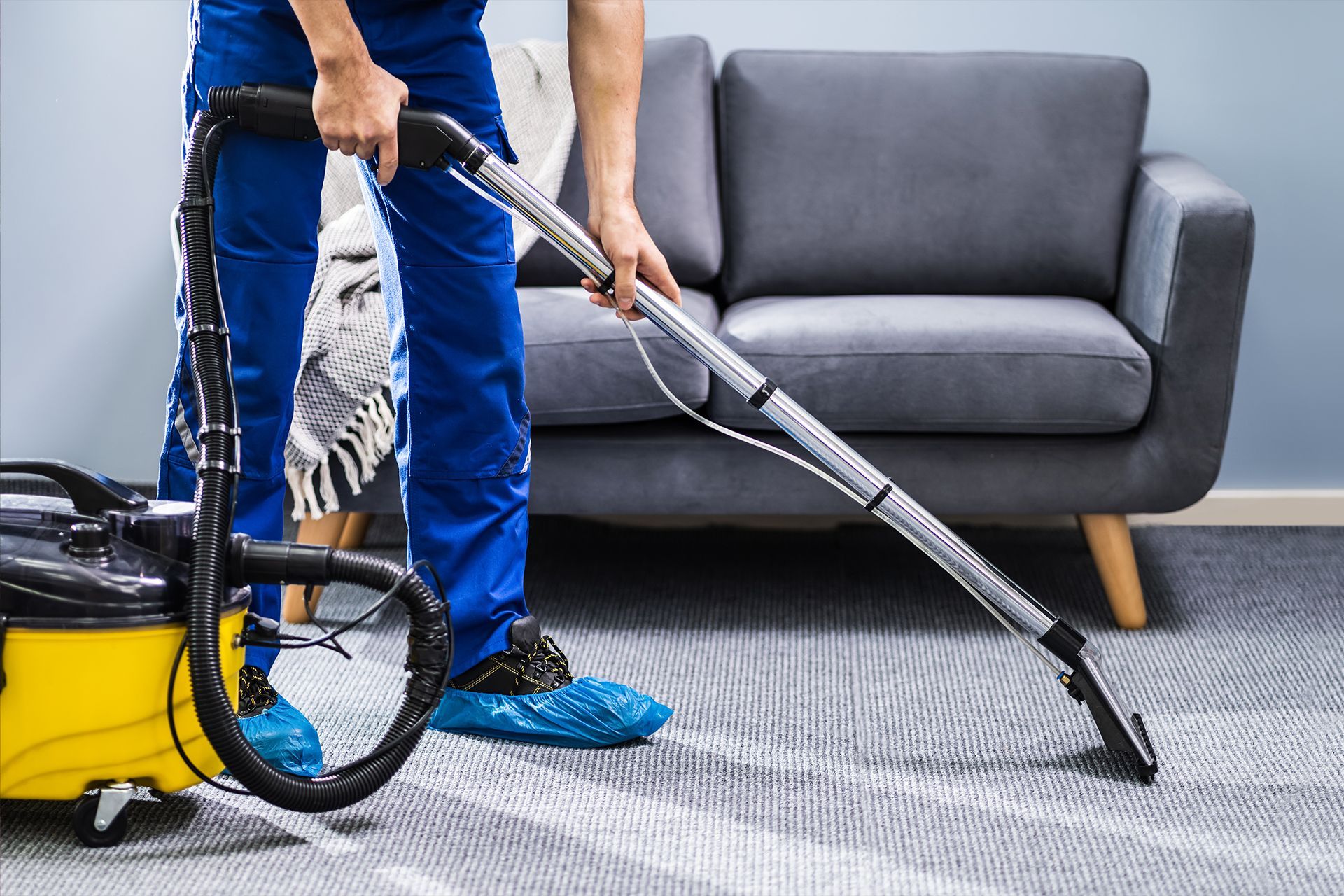 A man is using a vacuum cleaner to clean a carpet in a living room.