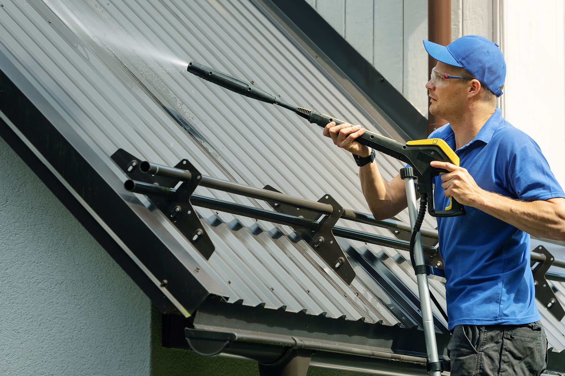 A man is cleaning the roof of a building with a high pressure washer.