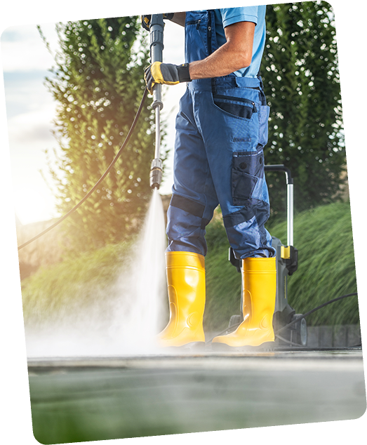 A man in blue overalls and yellow boots is using a high pressure washer.