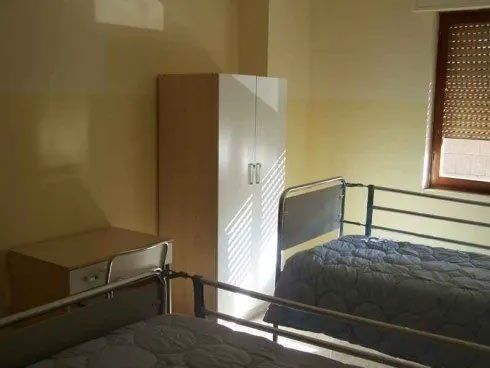 Una camera da letto con due letti, un armadio e una finestra.