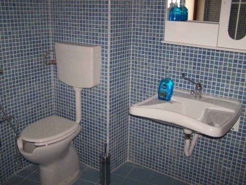 Un bagno con wc, lavandino e specchio.