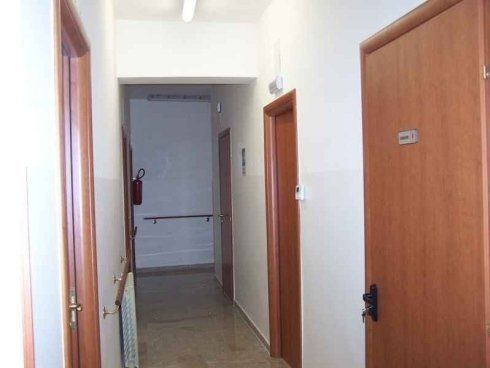 Un corridoio con porte di legno e una parete bianca