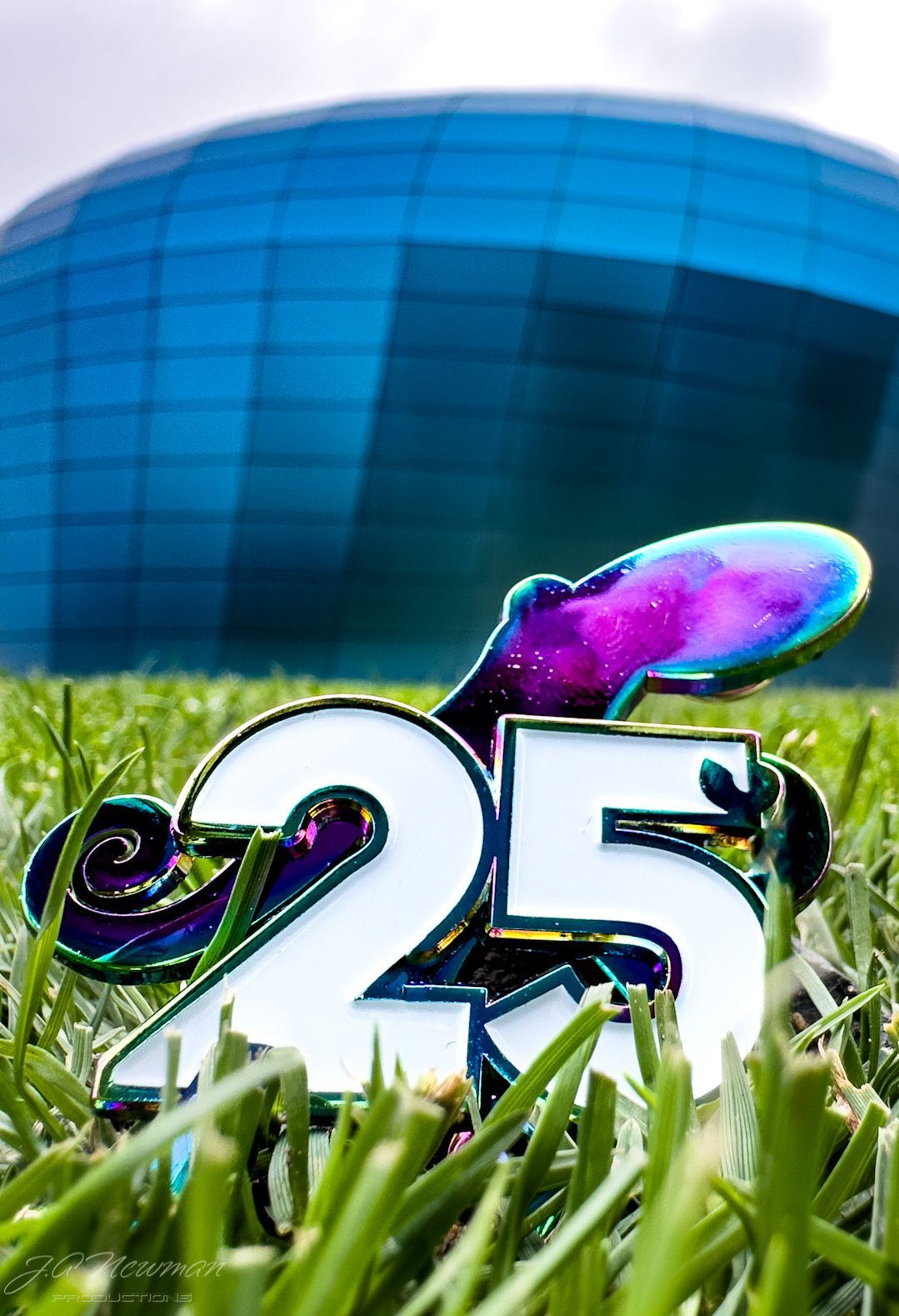 A 25-shaped emblem with an octopus design in grass, with a large blue dome in the background.