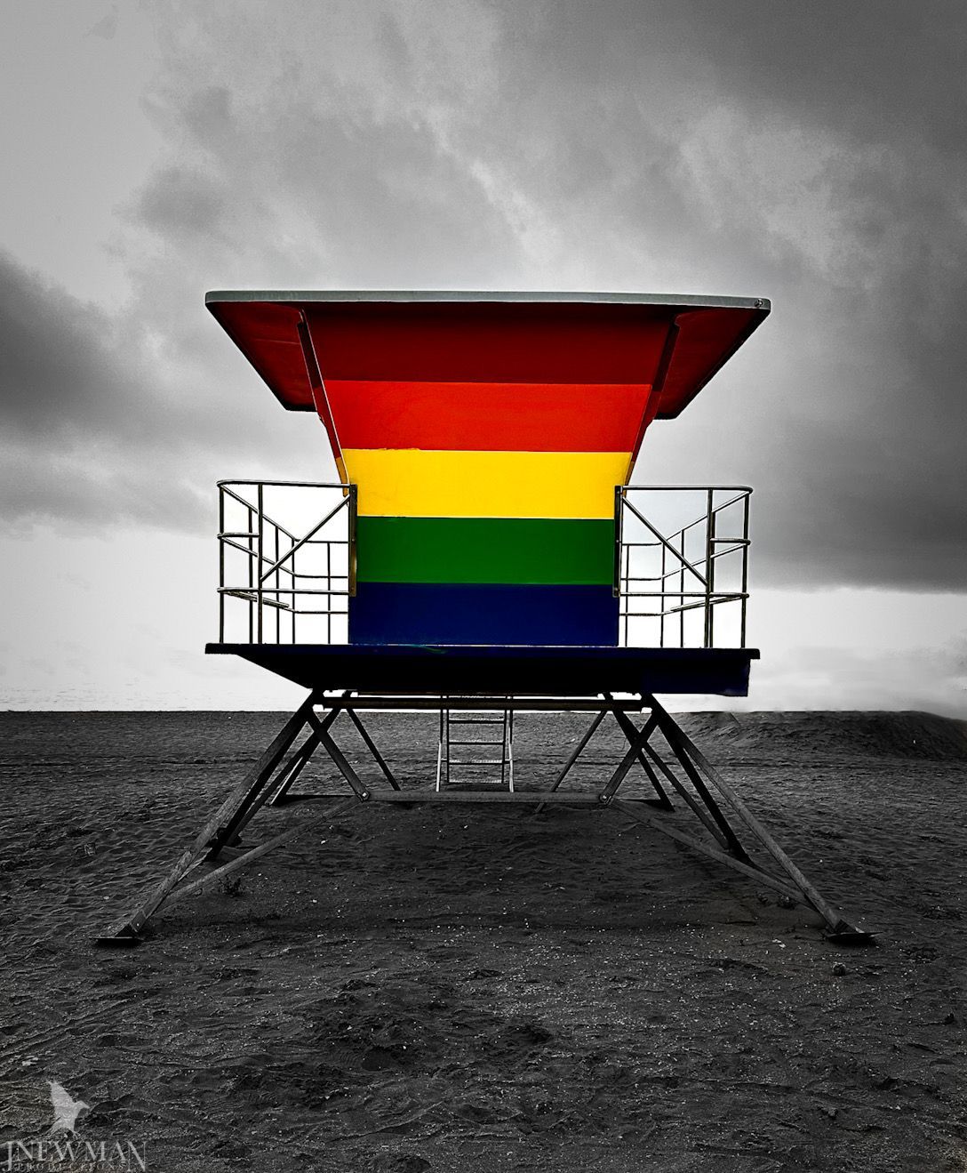 Lifeguard stand, rainbow colors, against black and white landscape.