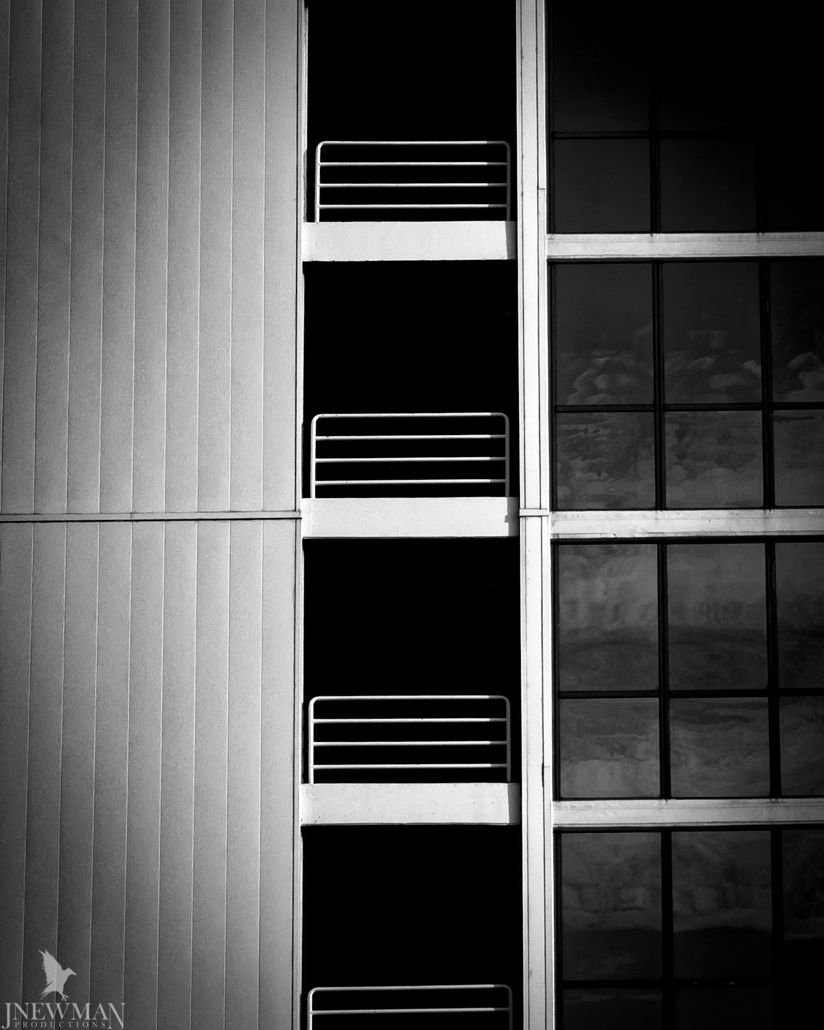 Black and white shot of a building facade with balconies and grid of windows.