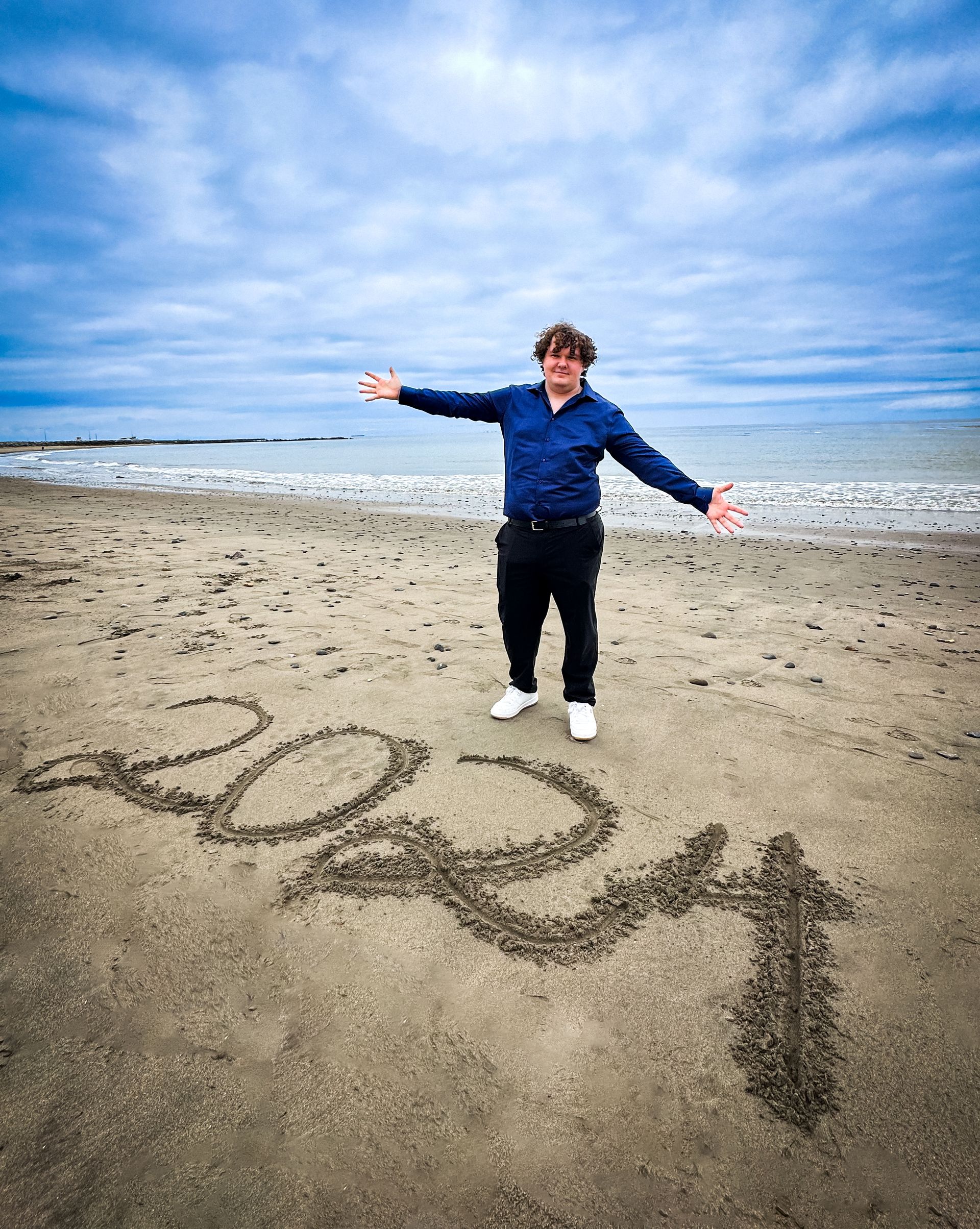 Man on beach with arms outstretched, standing near 