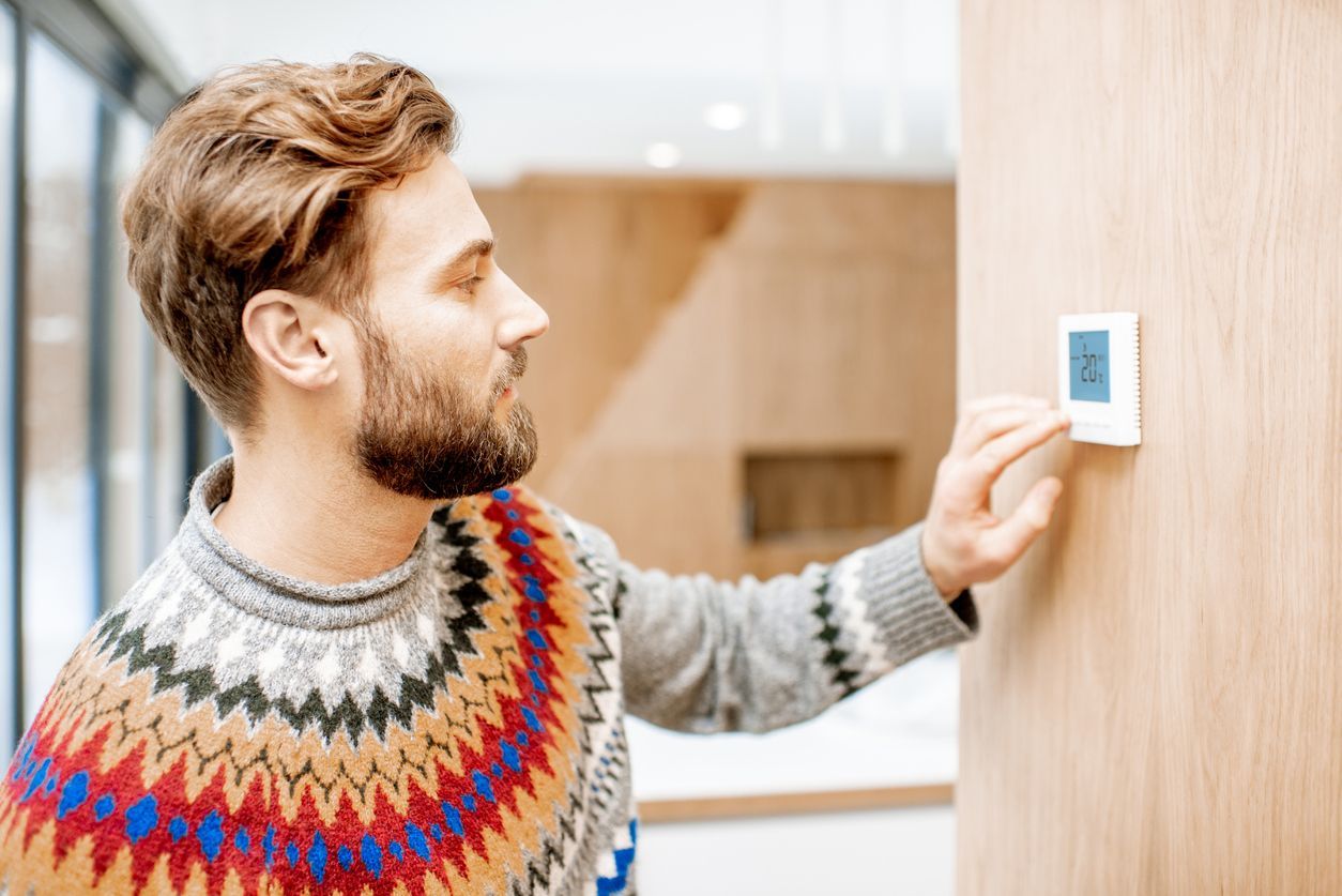 Man adjusting temperature with thermostat at home.