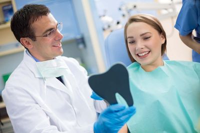 Dentist show teeth to girl with mirror—Established Dentistry Center in Fountain Valley, California