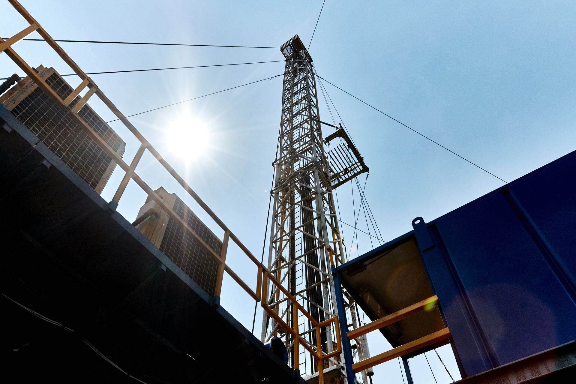 Looking up at an oil rig with the sun shining through it