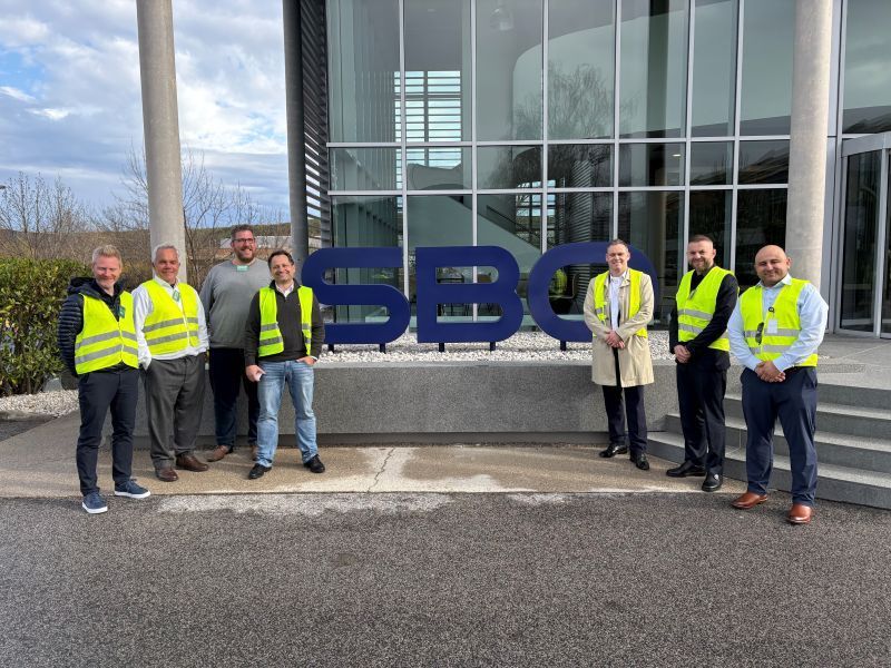 A group of people in yellow vests are standing in front of a building.