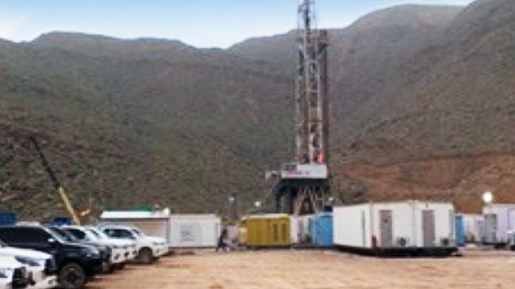 An oilrig with dirt mountains in the background