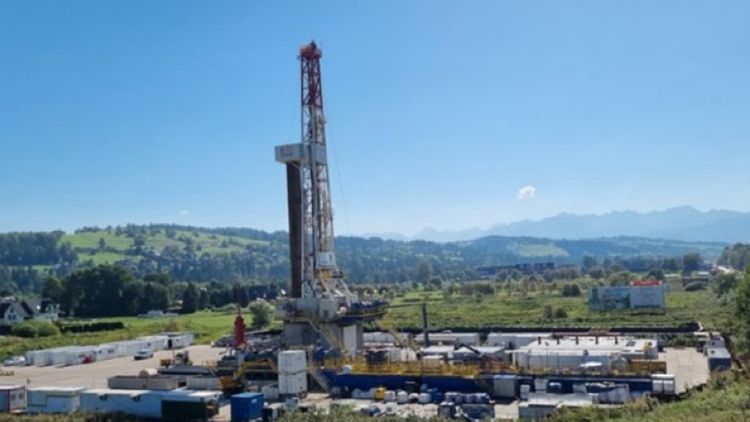 a large land oil rig in the middle of green fields background, poland