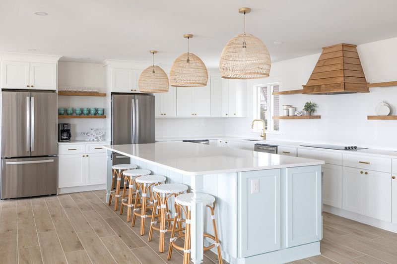 A kitchen with white cabinets , stainless steel appliances , a large island and stools.