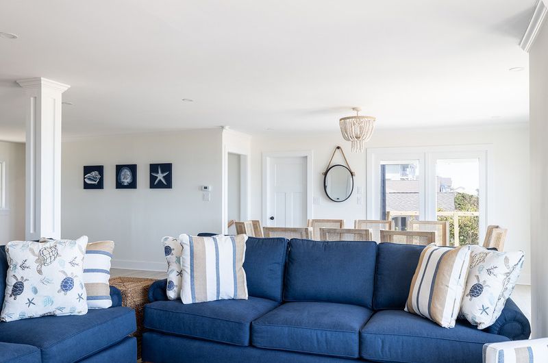 A living room with a blue couch and white pillows.