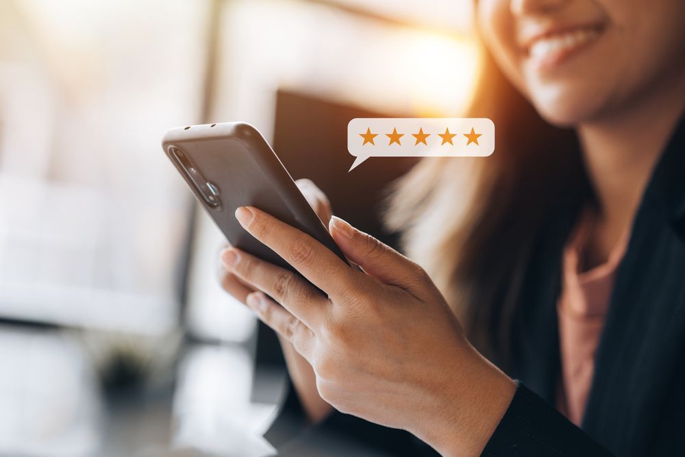 A woman is holding a cell phone with a speech bubble that says five stars.