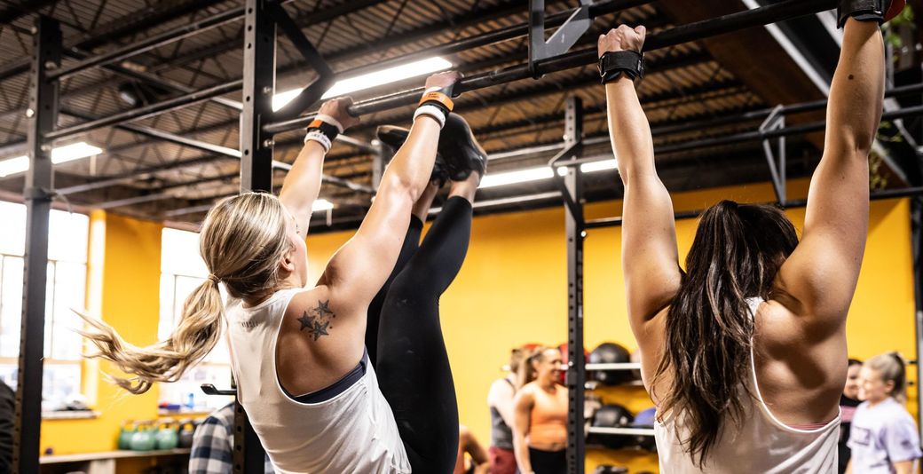 Two women doing pull ups in the gym