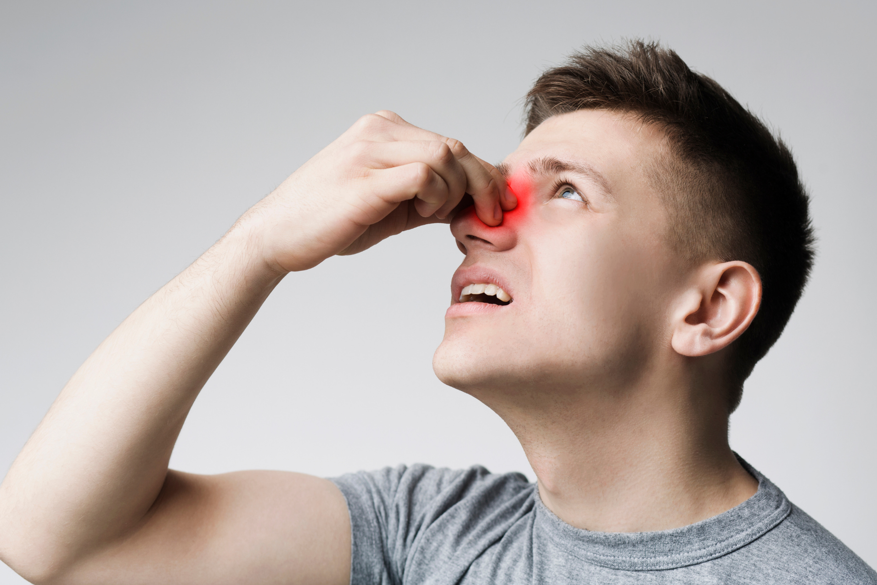 Young man touching painful, inflamed nose area - a typical symptom of VEXAS syndrome, which mostly affects men