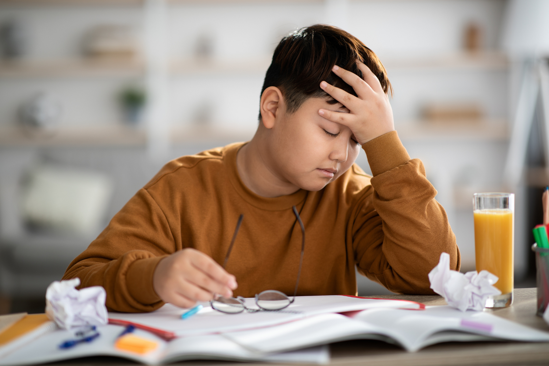 Young boy showing fatigue and difficulty concentrating during schoolwork, a common struggle for children with Juvenile Idiopathic Arthritis