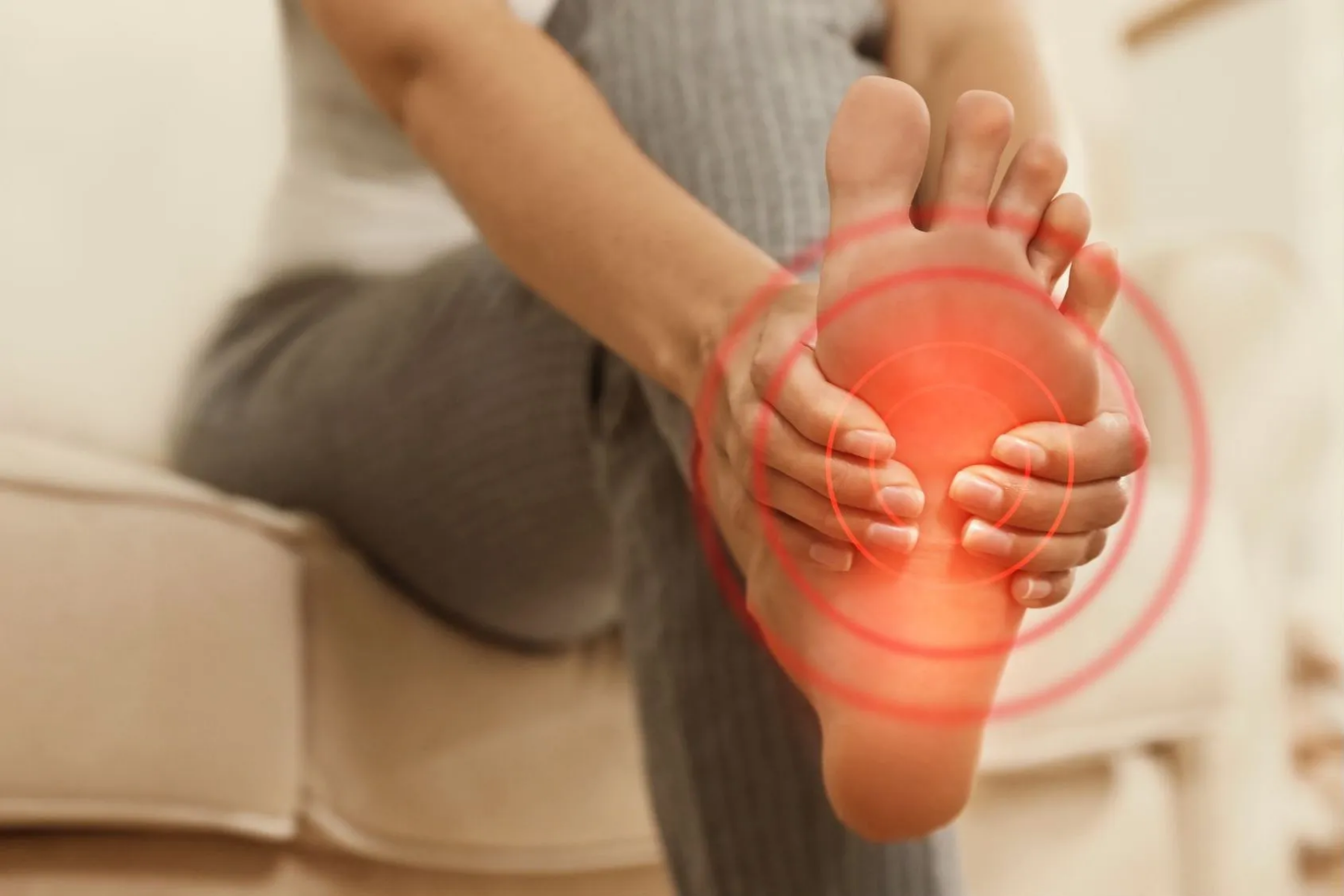 Person massaging foot with red glow effect highlighting psoriatic arthritis pain and inflammation in the toes, a common symptom of enthesitis and psoriatic arthritis.