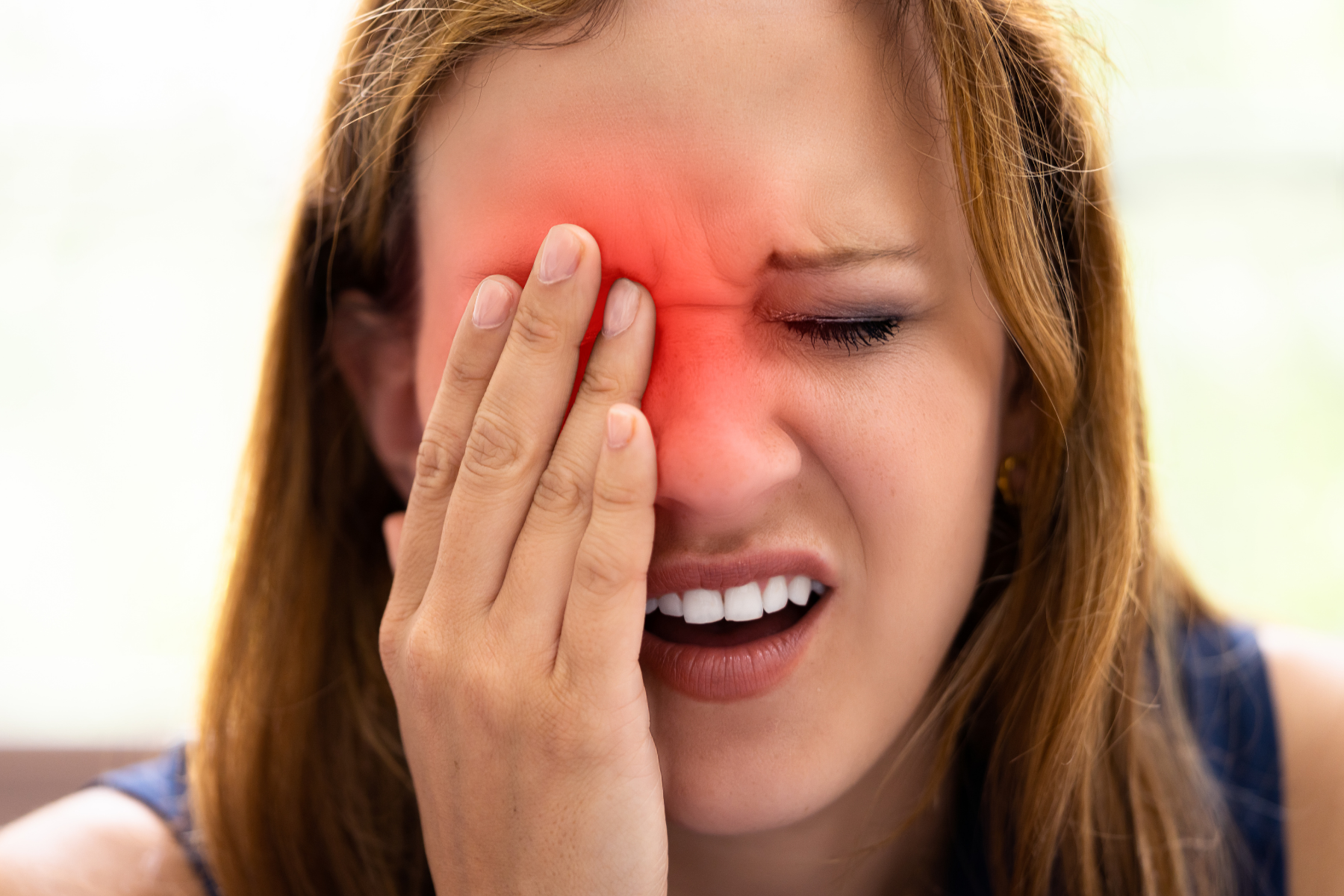 Woman experiencing severe facial pain and inflammation around the eye area, typical of CAPS episodes