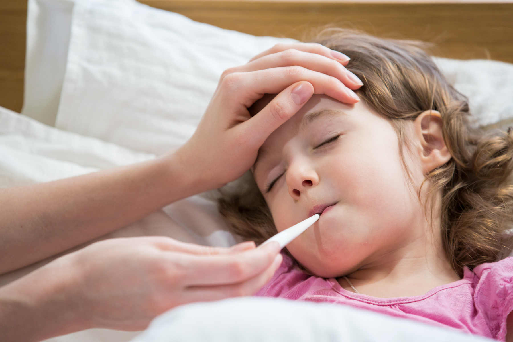 Young girl with fever having temperature checked, a common symptom during CNO/CRMO flares