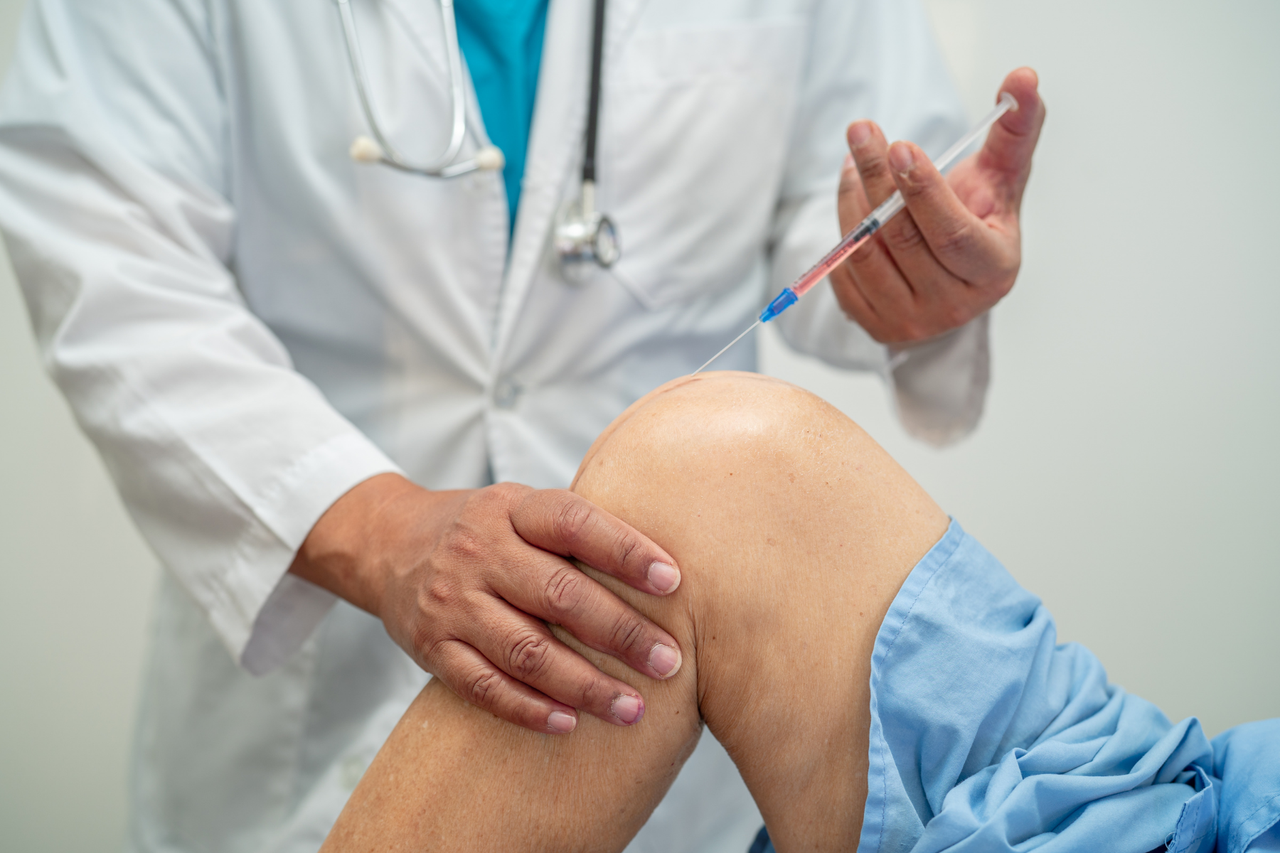 Doctor performing joint injection, a common treatment procedure for managing CNO/CRMO inflammation