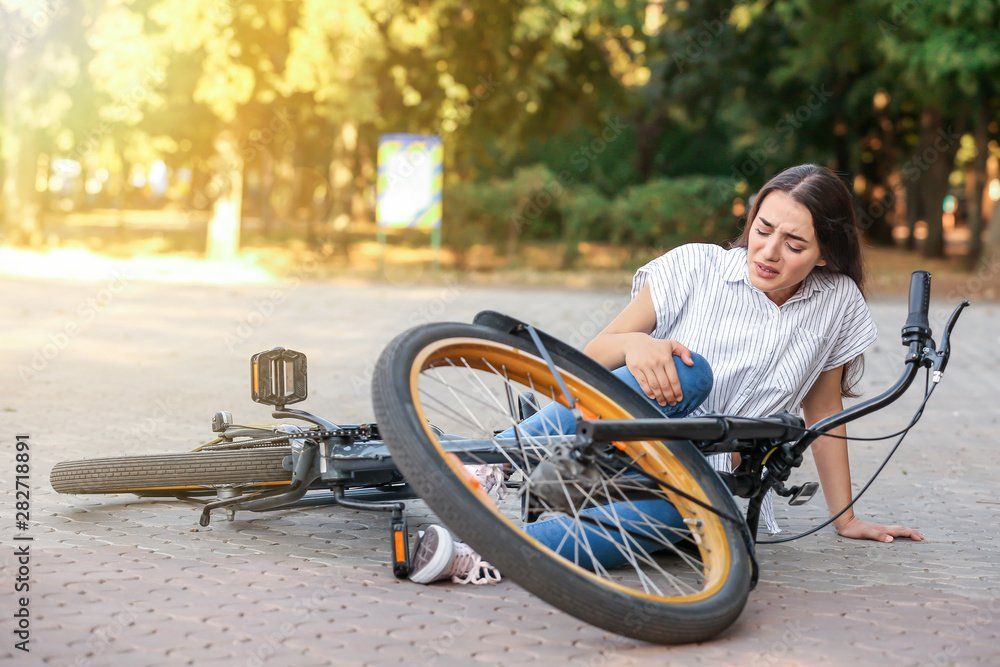 A person lying on the ground next to a fallen bicycle, illustrating the physical challenges and limitations that can come with arthritis