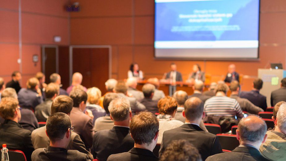 Out of focus image depicting a speaking engagement at a conference, representative of EULAR or ACR conferences.