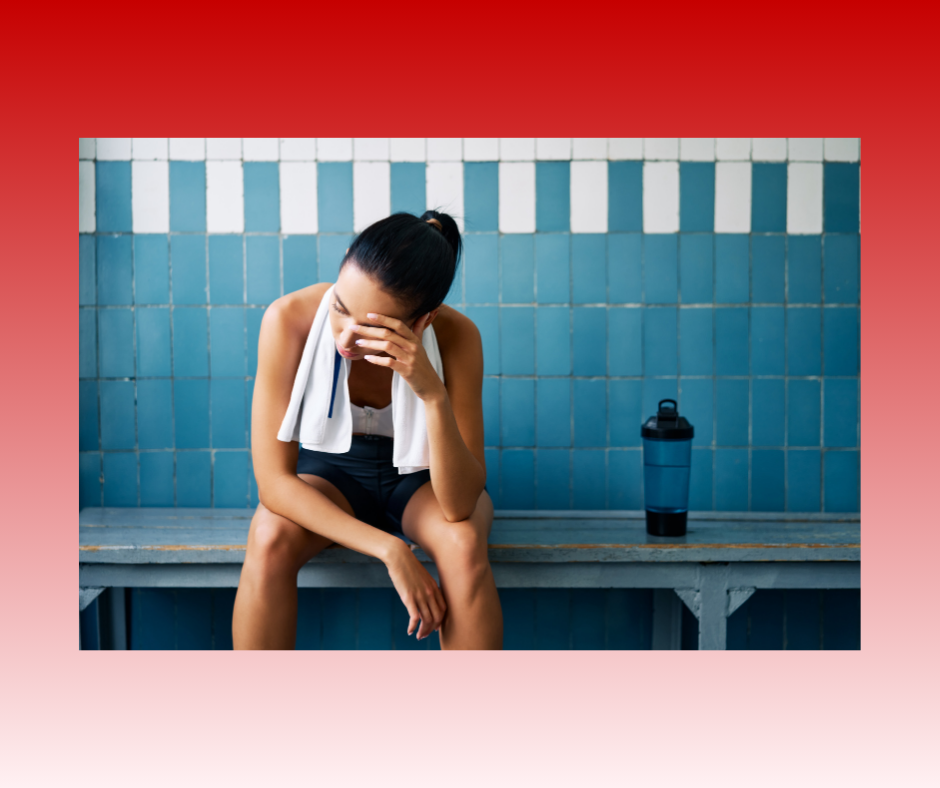 A person in athletic wear sits tiredly on a locker room bench, head in hand with a white towel