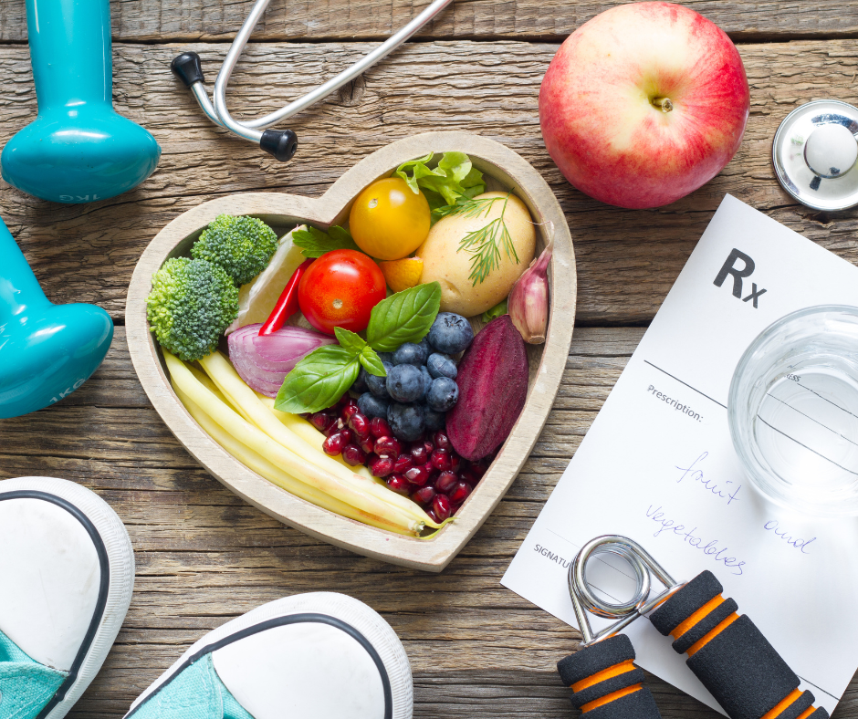 Table with blue shoes, blue dumbbell weights, heart bowl of fruit and a stethoscope. 