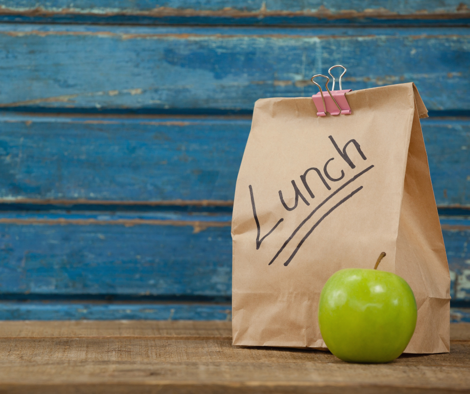 Paper bag with Lunch written across and it and an apple beside the paper bag