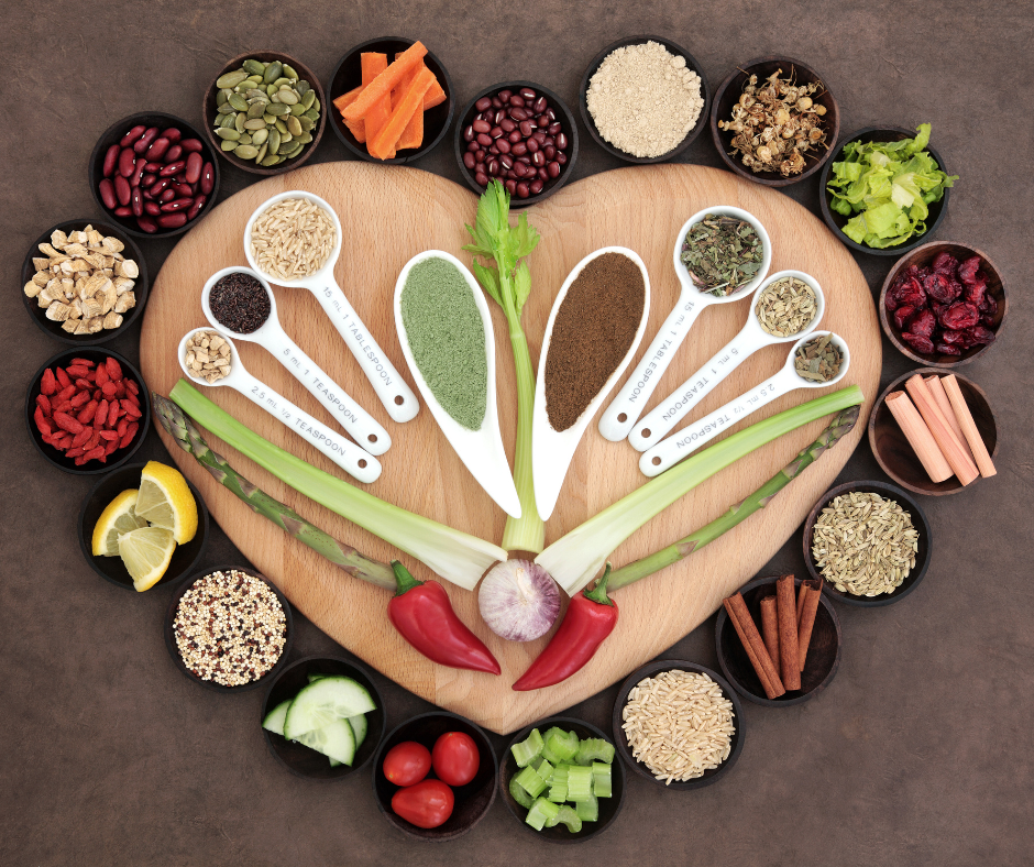 A heart-shape wooden board displaying measuring spoons of various spices and herbs anti-inflammatory