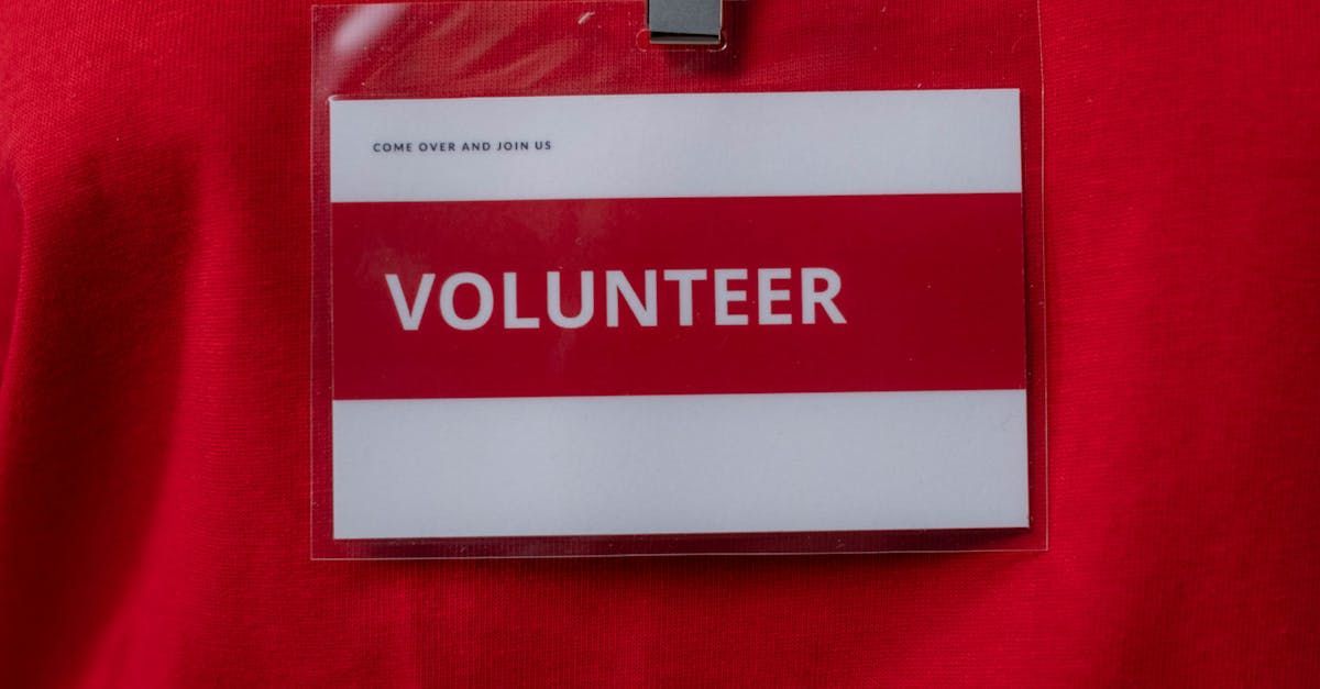 A close-up of a red and white volunteer badge with 'Come over and join us' text, symbolizing opportunities to join the aiarthritis volunteer team and make a difference in the autoinflammatory arthritis community