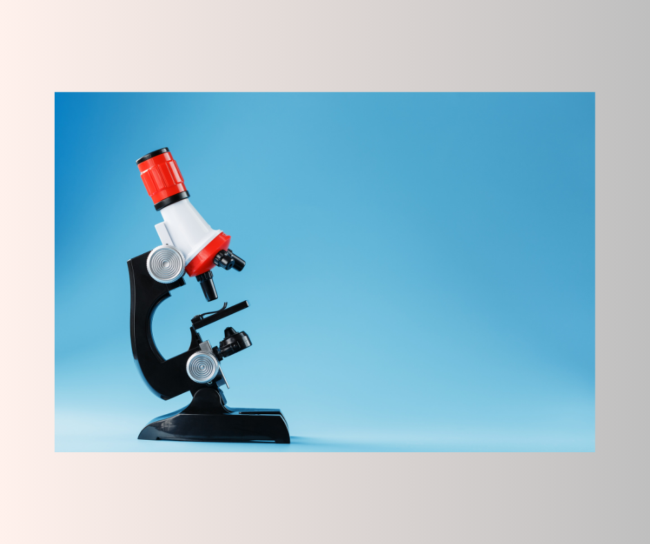 The black and red microscope is positioned in the side profile view against light blue background.