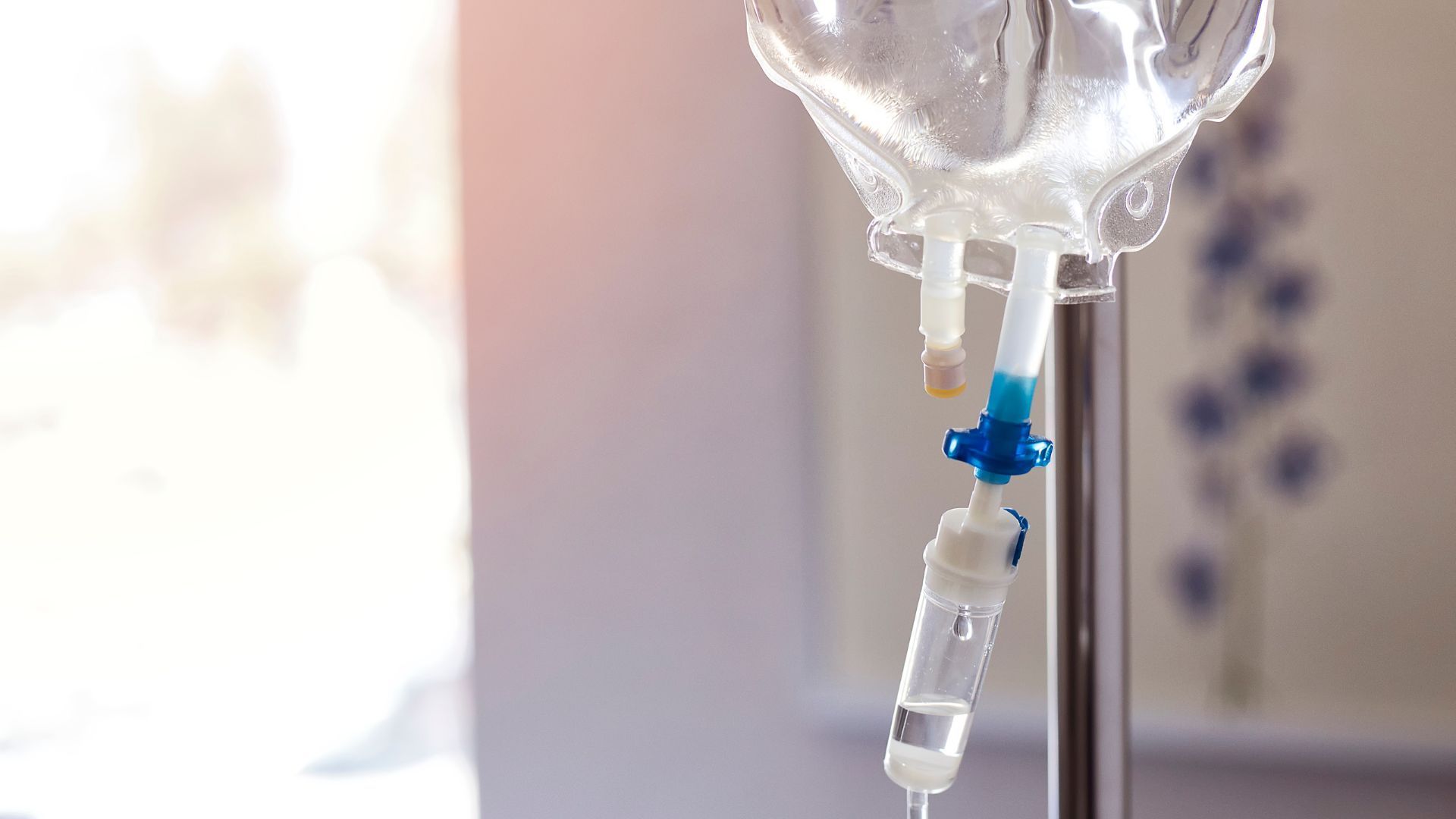 IV drip bag hanging on a stand in a softly lit hospital room