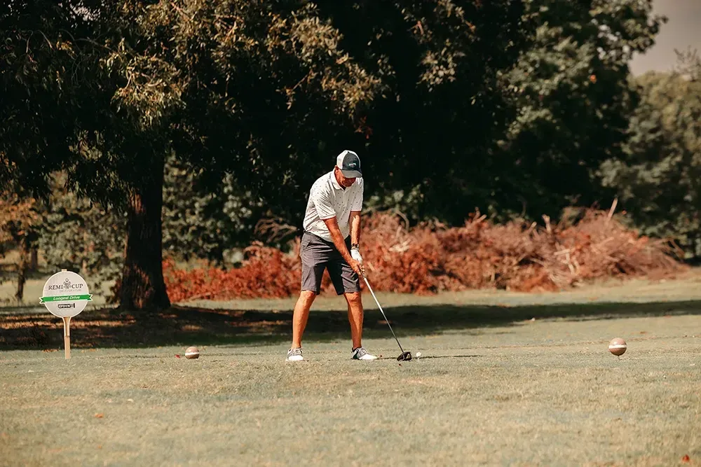A man is swinging a golf club on a golf course.