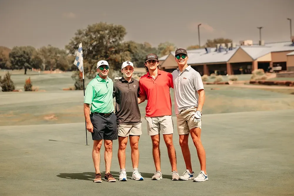 A group of men are posing for a picture on a golf course.