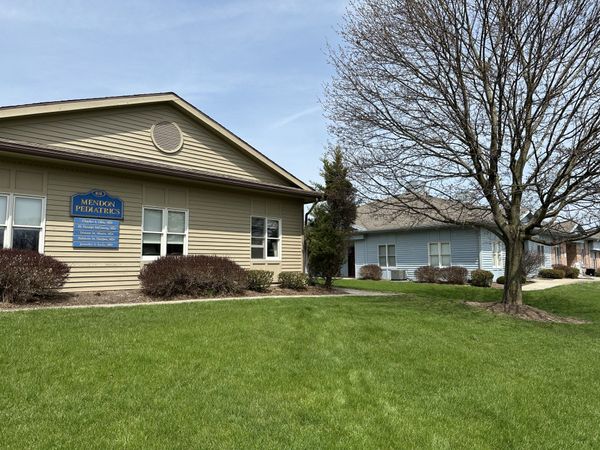 A house with a lot of windows and a large lawn in front of it.