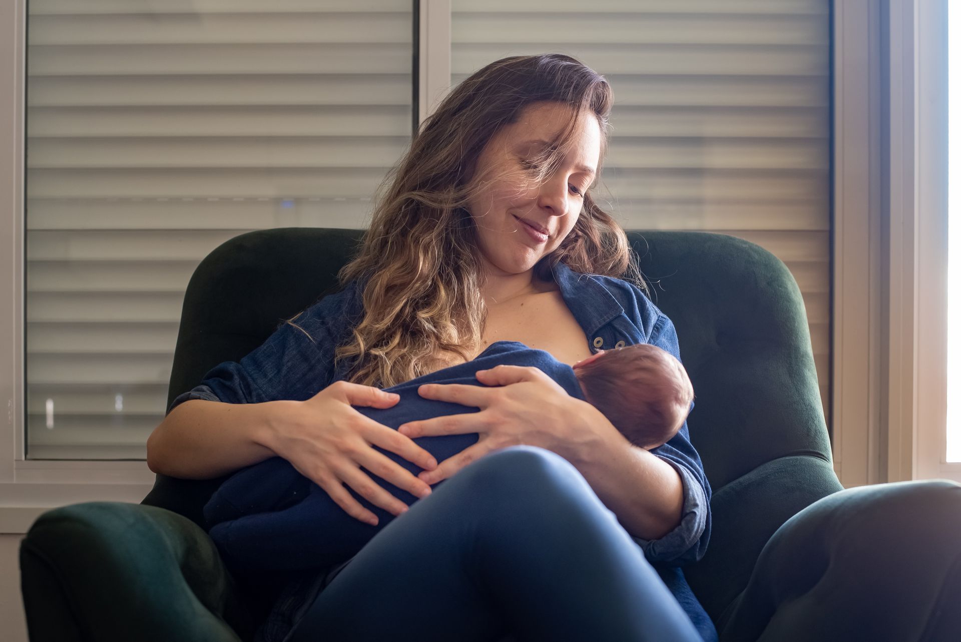 A woman is sitting in a chair breastfeeding a baby.