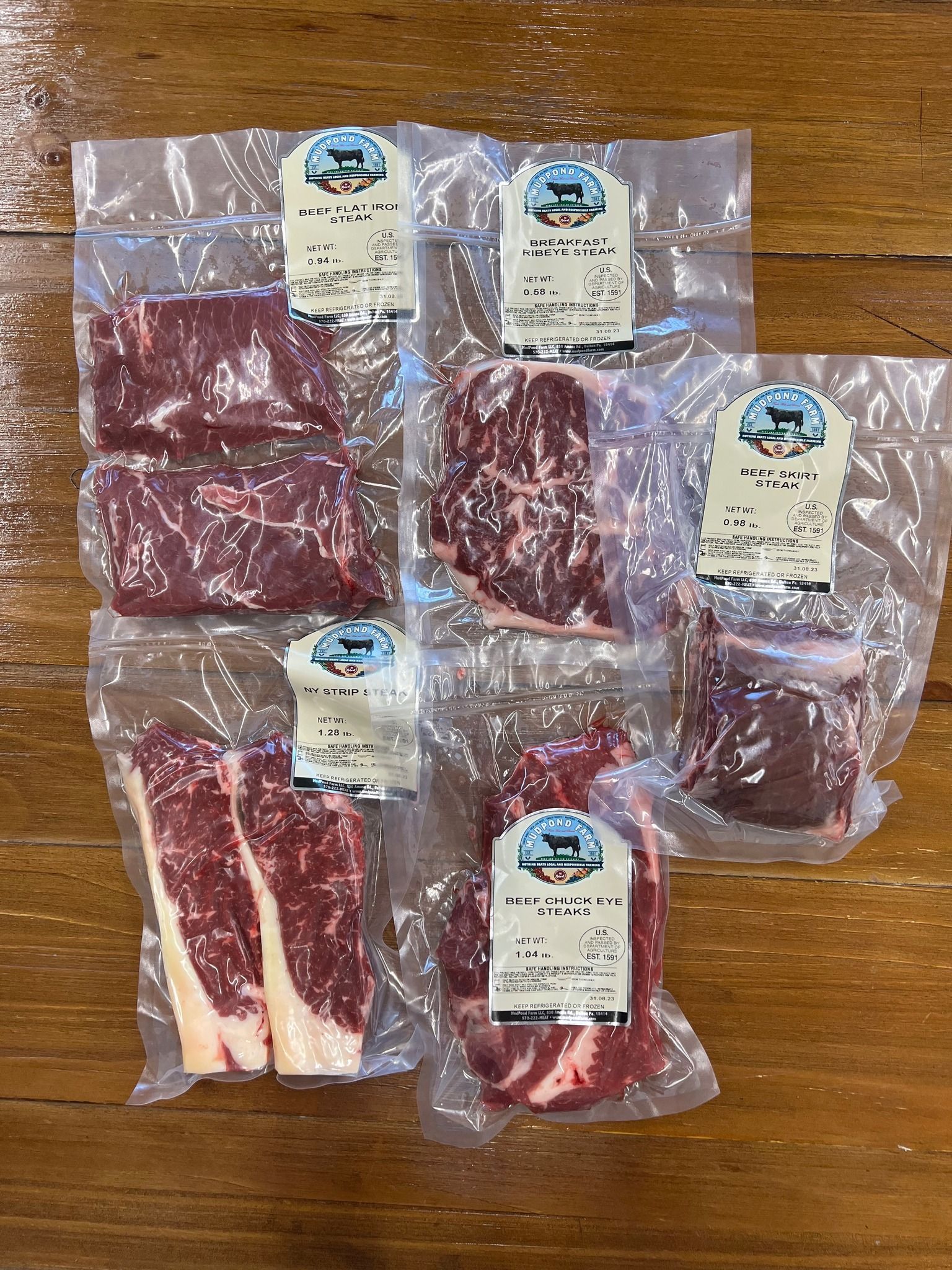 A bunch of meat in plastic bags on a wooden table.