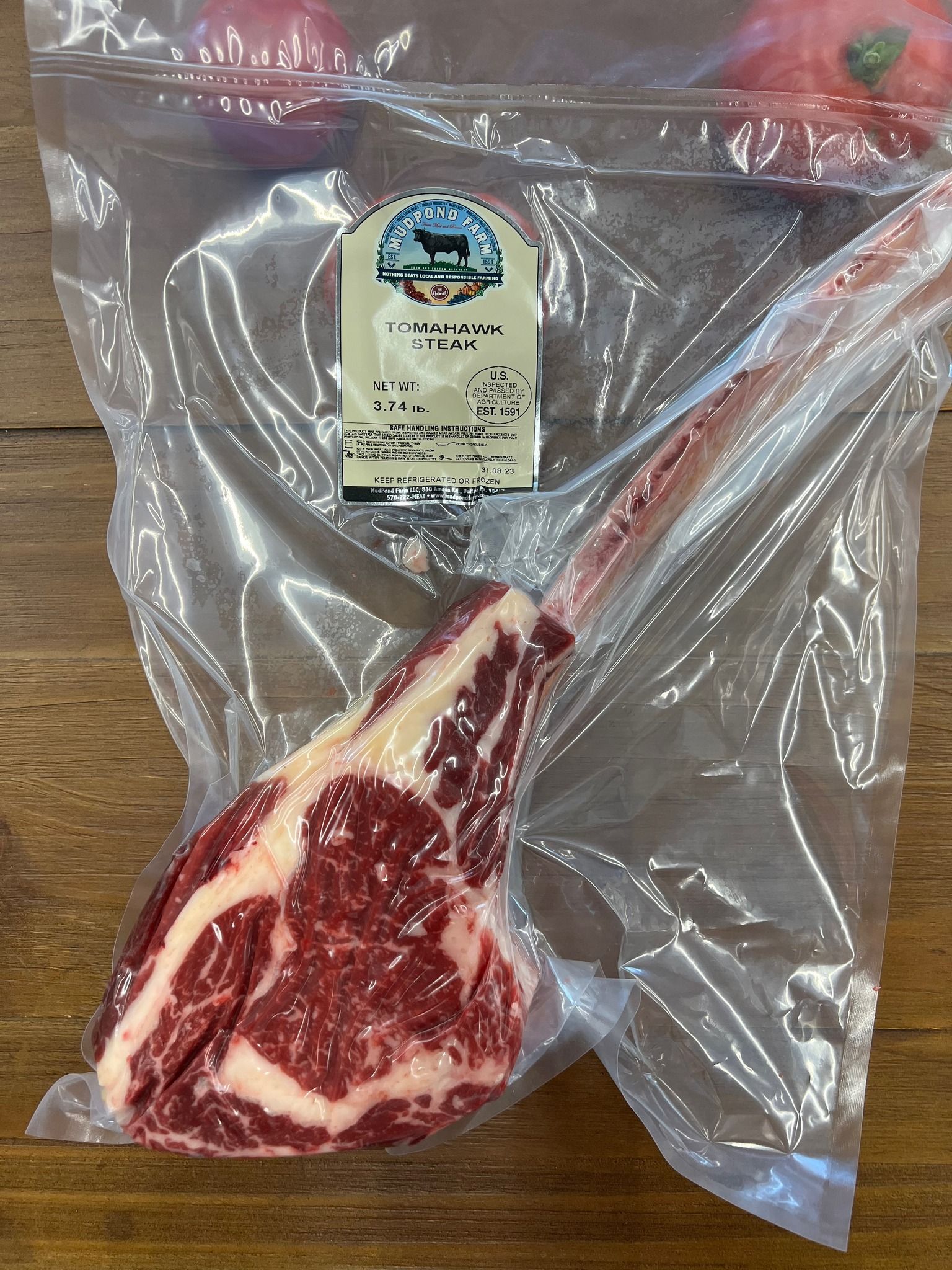 A steak is in a plastic bag on a wooden table.